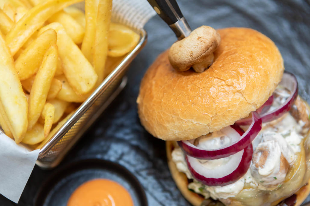 Fotografo food hamburger con cipolle su piatto nero e patatine fritte