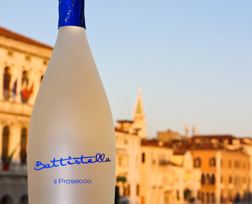 Bottiglia di prosecco con sullo sfondo una vista sfocata di venezia al tramonto