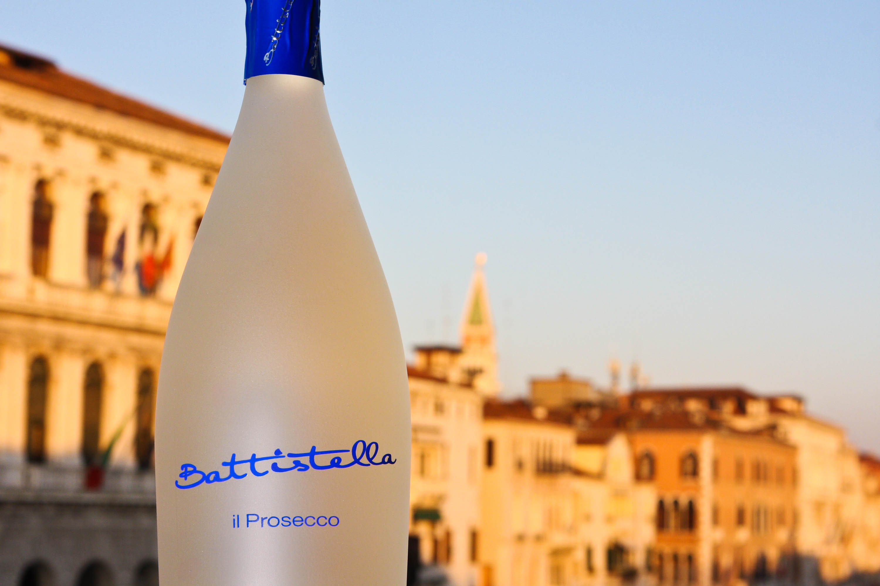 Bottiglia di prosecco con sullo sfondo una vista sfocata di venezia al tramonto